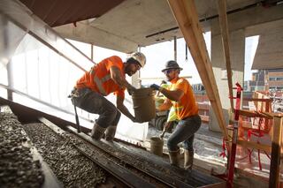 Two construction workers at jobsite pouring concrete to staircase
